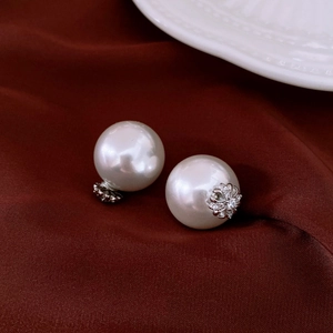 Detail of luxury pearl earring with flower-shaped diamond setting on red satin