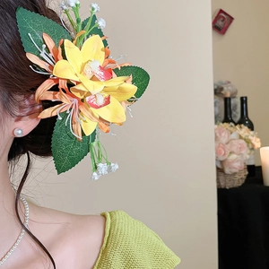 Detail of floral hair clip with yellow orchids and green leaves on an elegant model