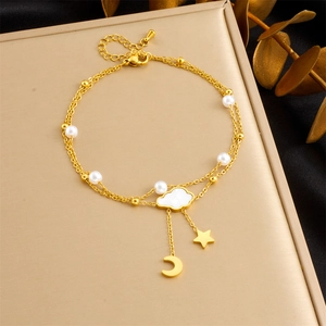 Detailed shot of gold layered anklet featuring white cloud, moon, and star charms with pearls