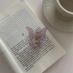 Detail of lavender butterfly hair claw clip with marble texture on an open book