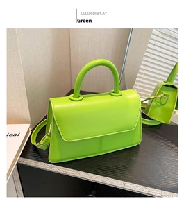 Detail view of neon green leather handbag with thick round handle on a wooden surface