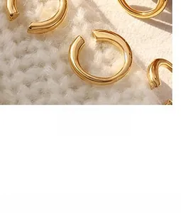 Macro shot of polished 18k gold-plated stainless steel hoop earrings on knit fabric