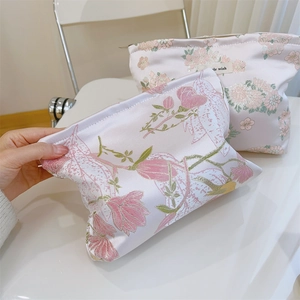 Details von Blumenstickerei auf rosa Satin-Kosmetiktaschen mit goldenem Reißverschluss