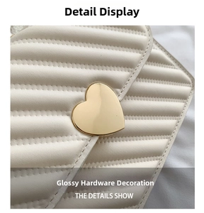 Detailed macro shot of the golden heart-shaped metal buckle on cream quilted leather bag