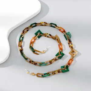 Macro detail of acrylic eyewear chain with colorful geometric links and golden metal clasps