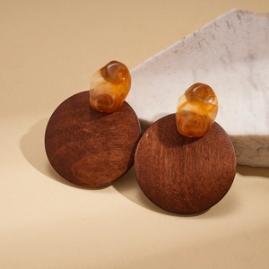 Boucles d'oreilles rétro avec disques en bois brun et résine ambre sur fond beige