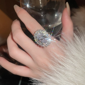Close-up of a gold-plated oval zircon ring with double-layered diamond halo on a model