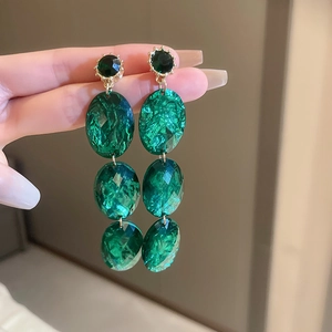 Three-tier oval emerald green drop earrings featuring golden metal with faceted resin