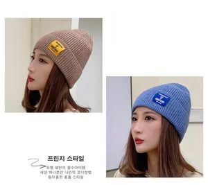 Detail of knitted beanie with Moment of Ambitions patch in brown and blue colors