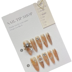 Handmade almond press-on nails in translucent iced coffee brown with pearl and heart charms