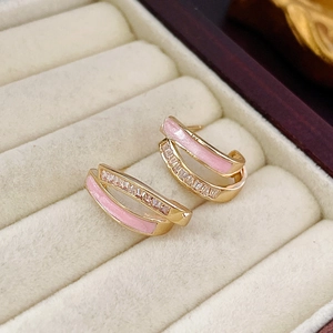 Nahaufnahme goldener C-förmiger Ohrringe mit rosa Emaille und Zirkonia in Samtbox