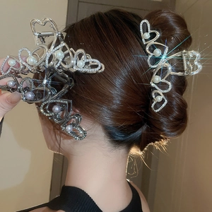 Détail de trois pinces à cheveux en forme de cœur avec strass et perles sur une coiffure