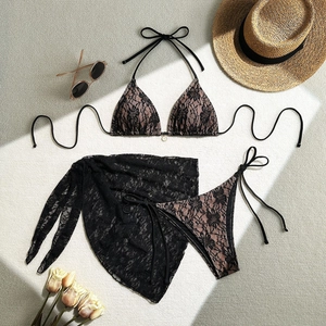 Flat lay of a three-piece lace bikini set with matching floral sarong and beach accessories