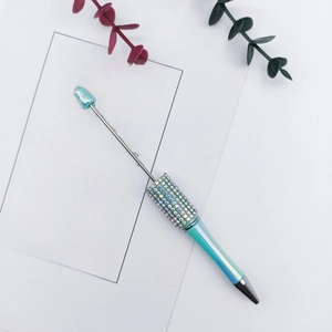 Creative beaded pen with colorful rhinestones and light teal finish on white background