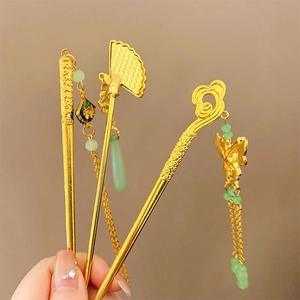Detail of traditional Chinese gold hairpins with green jade beads and enamel tassels