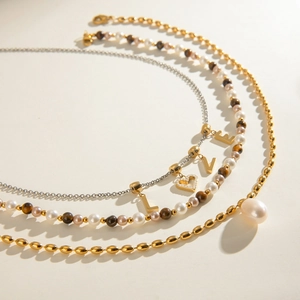Detail of layered stainless steel necklace with LOVE charms and freshwater pearl pendant
