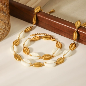 Detailed close-up of golden shell necklace and bracelet set on a light background