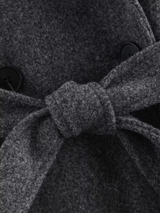 Detailed macro view of a dark grey wool coat featuring a tied belt and black buttons