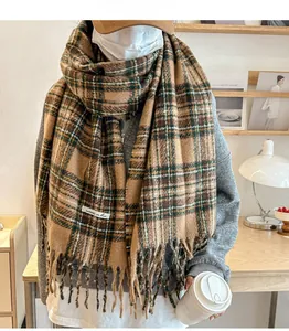 Detailed close-up of thick plaid scarf with tassels and brand label on a cozy table