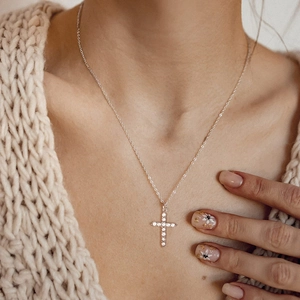 Close-up of silver cross pendant with sparkling zircons on a delicate O-link chain