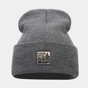 Detailed knit texture of dark grey beanie featuring a vintage denim supplies fabric patch