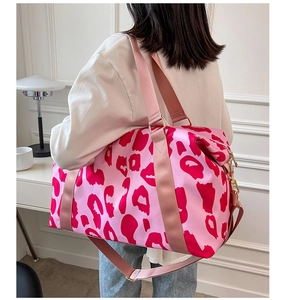 Side view of a pink leopard print oxford cloth travel bag worn by a model in a room