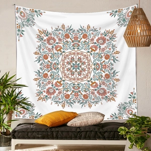 Bohemian mandala tapestry with floral patterns hanging over a black futon on white wall