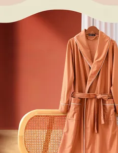 Detail of orange-brown satin bathrobe featuring a textured grid weave and white piping trim