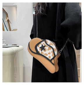 Detail of cowboy hat-shaped crossbody bag with cow print decor and silver chain