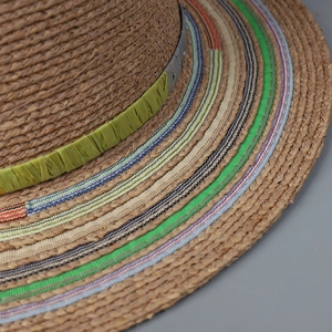 Close-up of the woven raffia texture and colorful striped ribbon on the summer sun hat