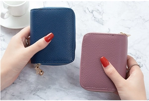 Detalle de tarjeteros en cuero granulado azul marino y rosa con cremalleras doradas finas