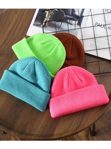 Close-up of four colorful knit beanies featuring detailed thick-knit texture on dark wood