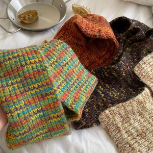 Stacked coarse knit scarves in colorful striped, orange, purple, and beige wool textures
