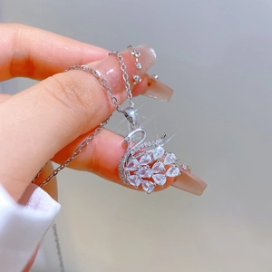 Macro shot of a silver swan pendant with sparkling zircons held by a model