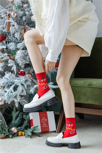 Détail de chaussettes de Noël rouges avec lettrage blanc et mocassins blancs épais