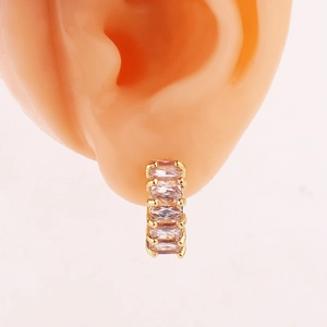 Close-up of golden huggie earrings with five rectangular cubic zirconia stones on model