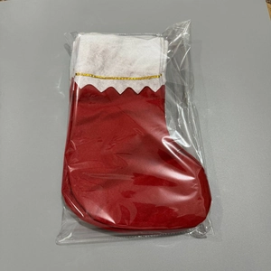 Close-up of a red Christmas stocking with white cuff and gold trim in plastic packaging