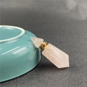 Detailed close-up of a hexagonal rose quartz perfume bottle pendant with a golden metal cap
