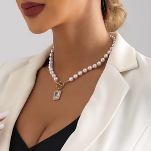 Detailed close-up of a pearl necklace with rectangle crystal pendant on a female model