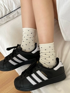 Gros plan de chaussettes à pois en coton avec des baskets classiques en cuir noir et blanc
