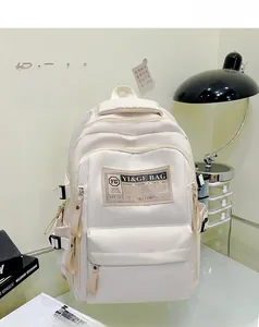 Detail view of the cream nylon backpack featuring side buckle straps and a logo woven label