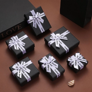 Close-up of black textured jewelry gift boxes with white Fashion Jewelry ribbons