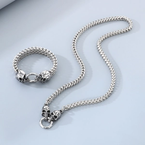 Silver punk skull chain necklace and bracelet set with metallic luster on gray background