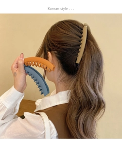 Three matte banana clips in khaki, orange and blue shown in a ponytail hairstyle