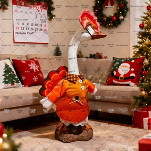Detail of goose figurine wearing orange polka dot outfit with a pumpkin bag in Christmas setting