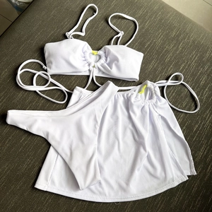 Detailed texture of white ribbed three-piece bikini featuring a yellow heart buckle