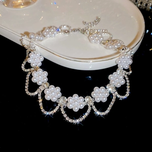Close-up of pearl flower necklace with silver rhinestone tassels on dark background
