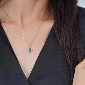 Nahaufnahme einer Halskette mit Zirkonia-Blütenanhänger und blauem Stein am Model