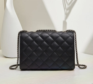 Detailed view of black quilted faux leather handbag with dark metallic chain strap