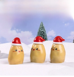 Three mini Christmas potato figurines with red hats in a snowy miniature landscape scene